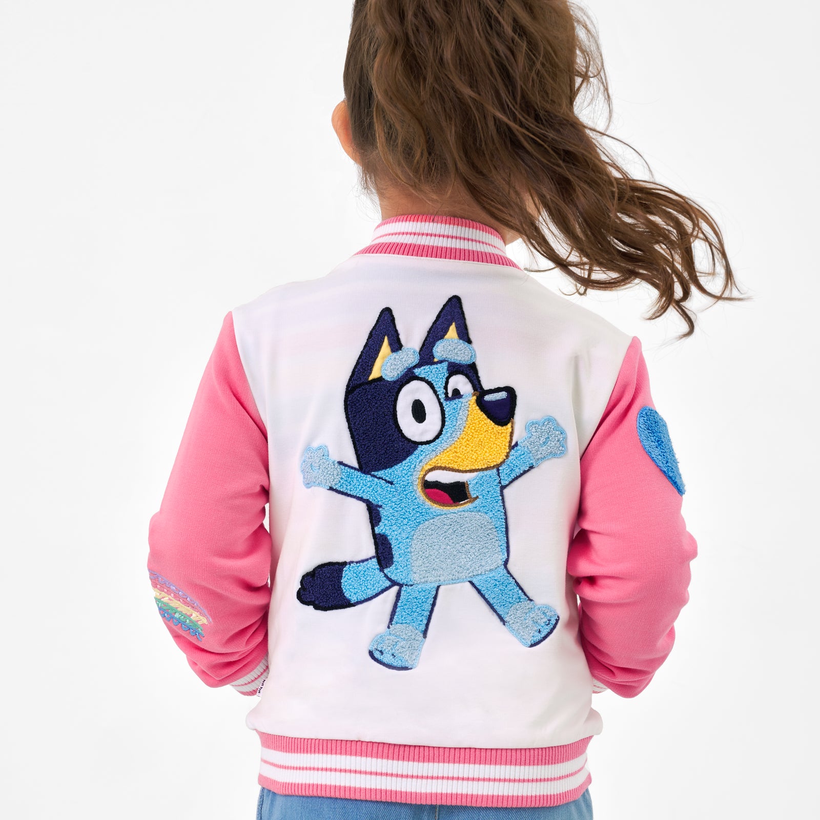 Close up back view image of a child wearing a Bluey pink bomber jacket