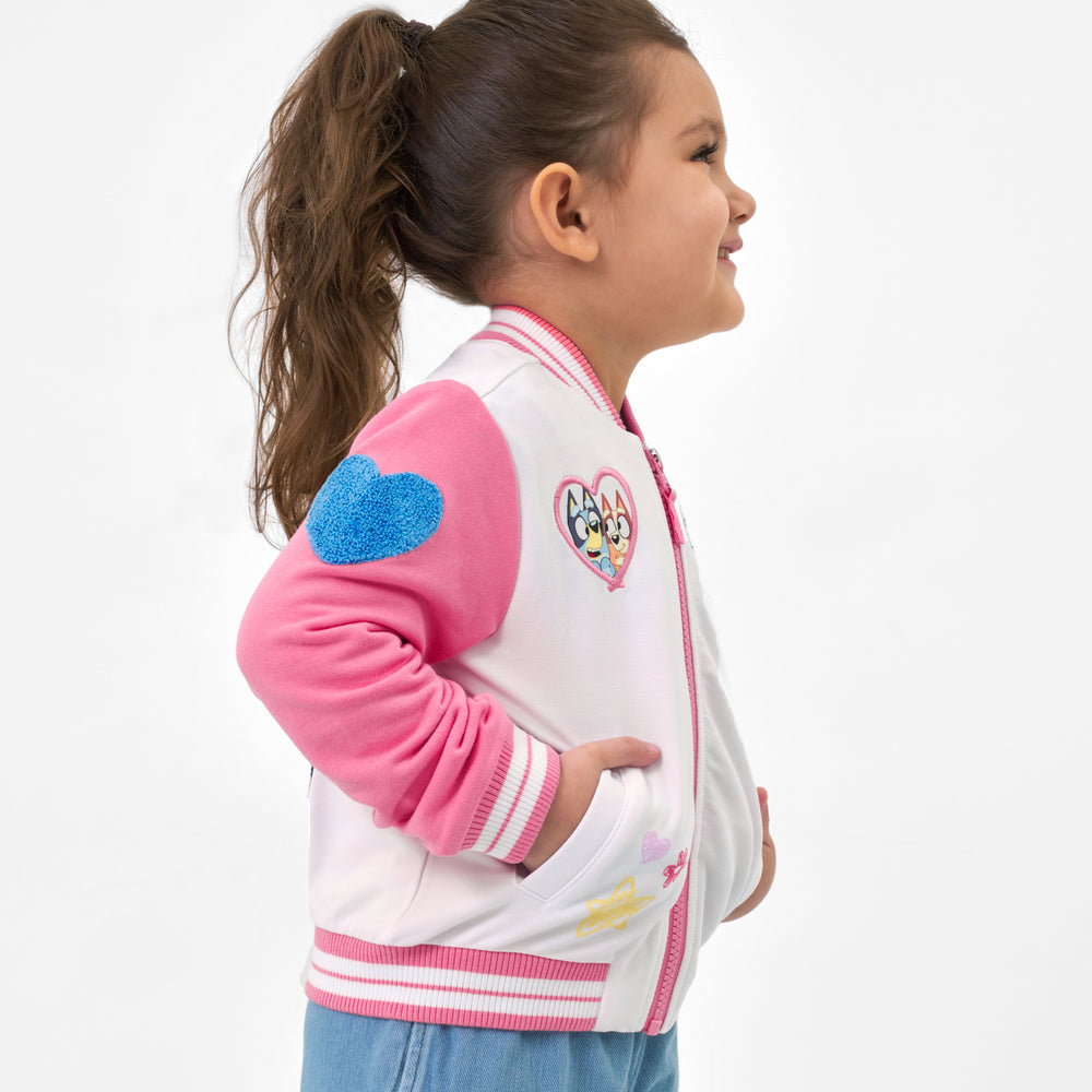 Girl wearing the Bluey Pink Bomber Jacket with hands in the pocket, displaying the side details