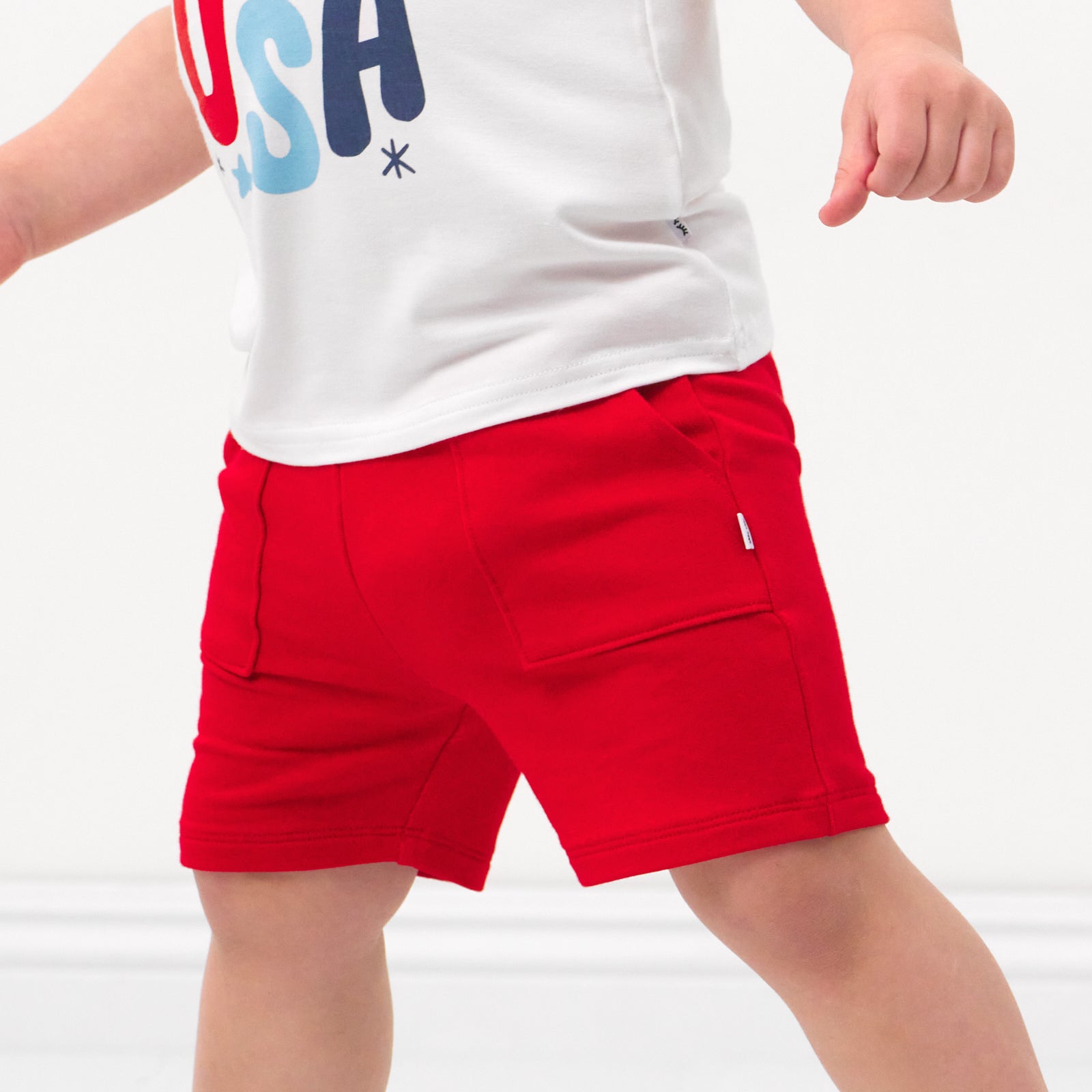 Close up image of a child wearing Candy Red shorts and coordinating Play top