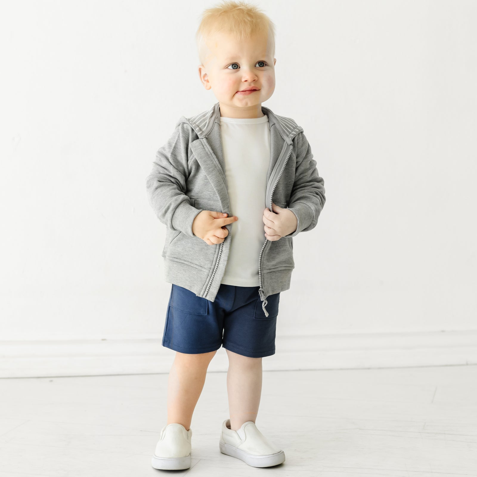 Child wearing Vintage Navy shorts and coordinating Play top and zip up hoodie