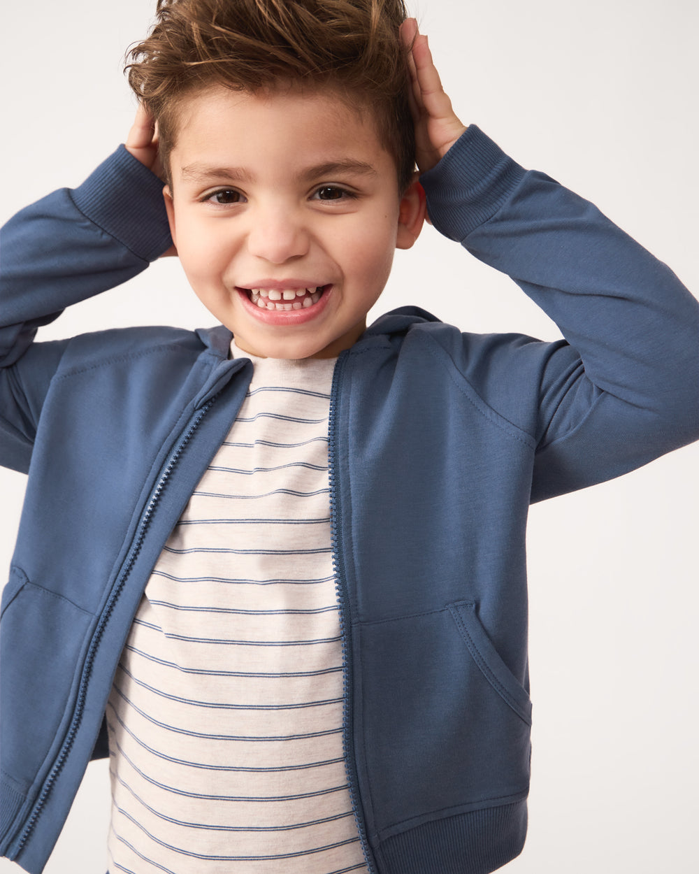 Close up of boy wearing the Vintage Navy Zip Hoodie layered over a striped tee