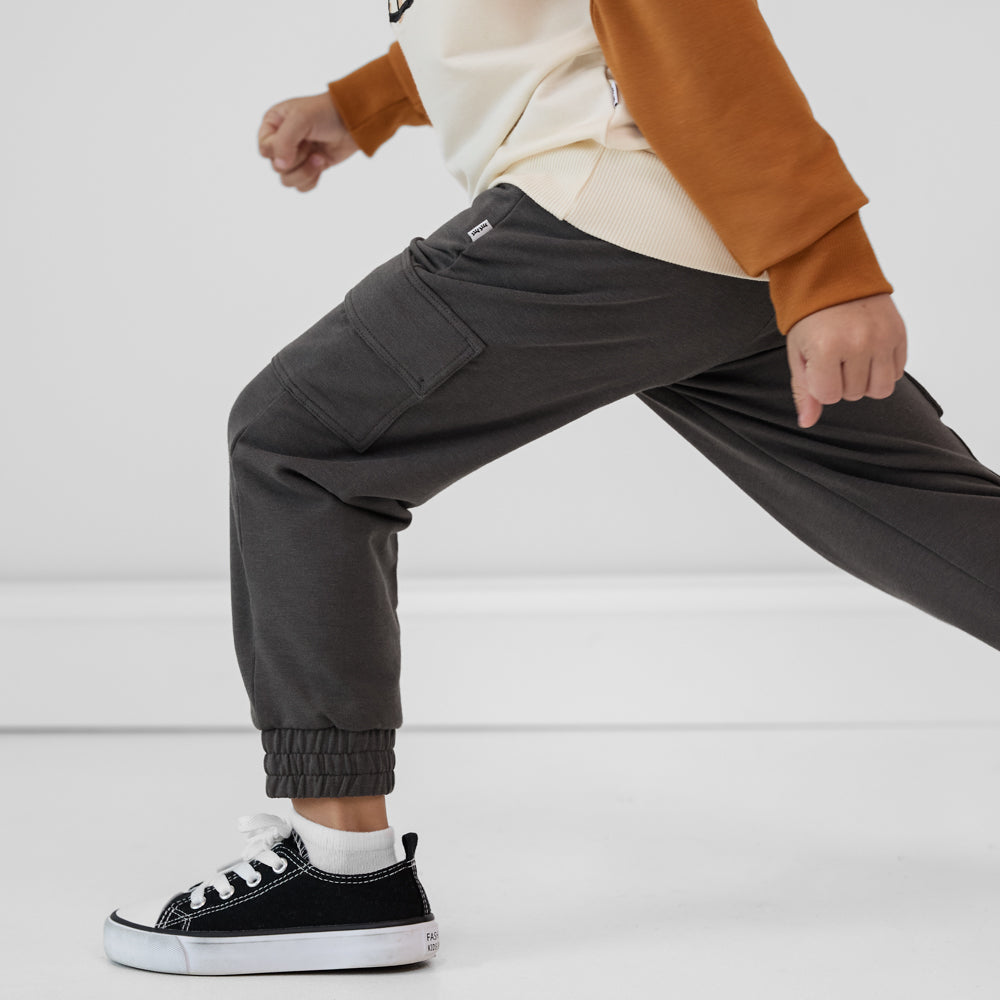 Close-up side view of a child running wearing Washed Black cargo joggers paired with a coordinating crewneck