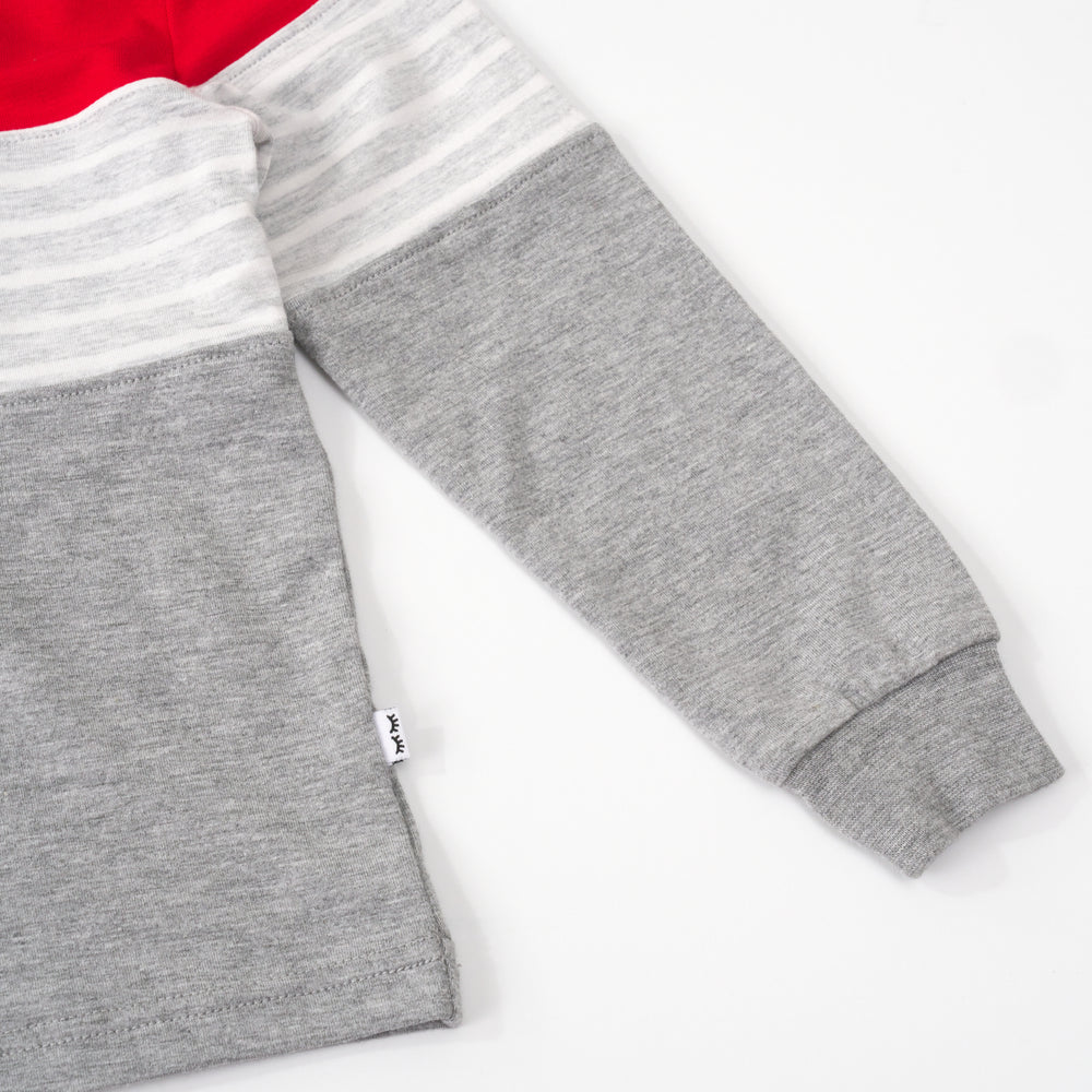 Close up flat lay of the sleeve and bottom hem of a candy red colorblock hooded tee