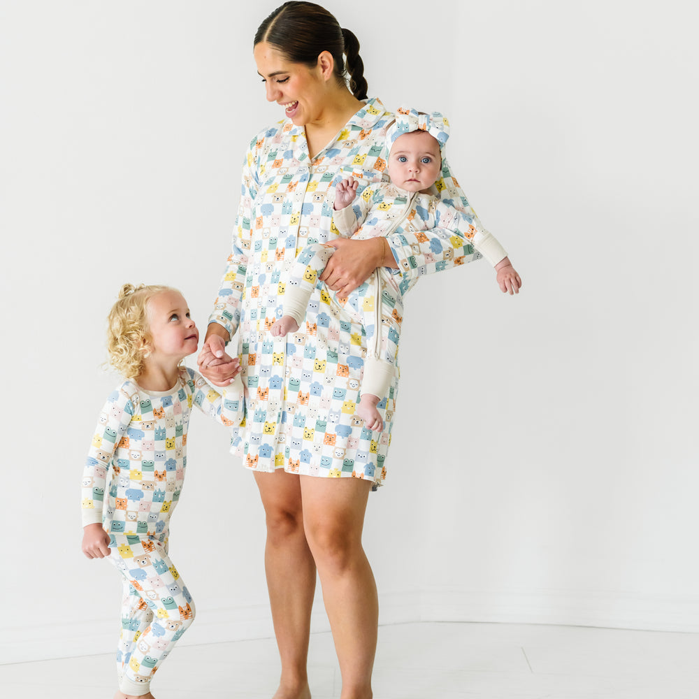 Woman and her two children wearing matching Check Mates printed pjs. Mom is wearing a Check Mates women's sleep shirt, her kids are wearing two piece and zippy styles paired with a luxe bow headband.