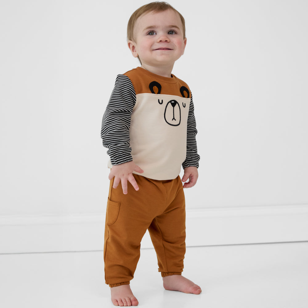 Child looking up and smiling wearing Golden Brown cinched joggers paired with a coordinating crewneck sweatshirt