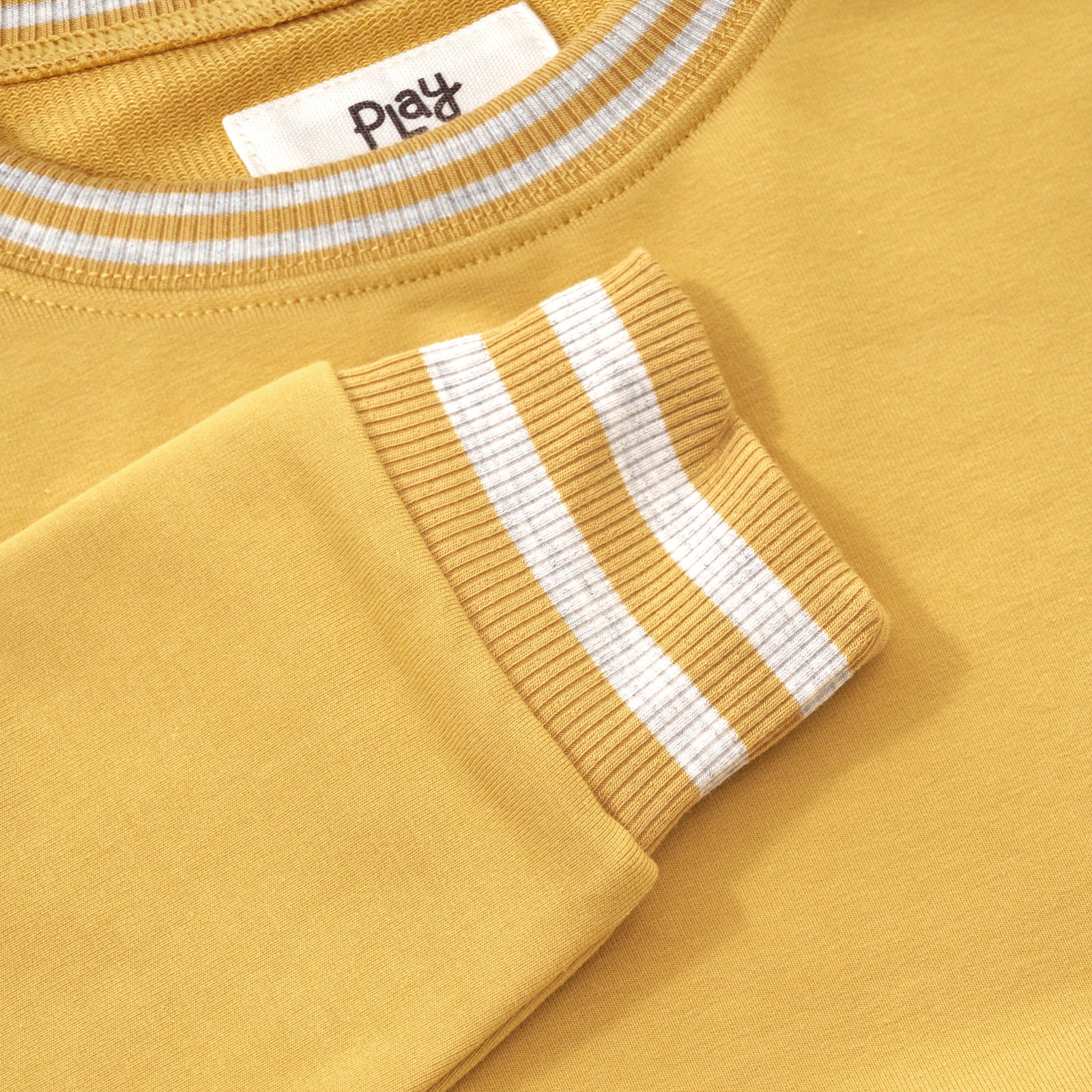 Close up flat lay image of the collar and sleeve detail on the Honey Pocket Crewneck