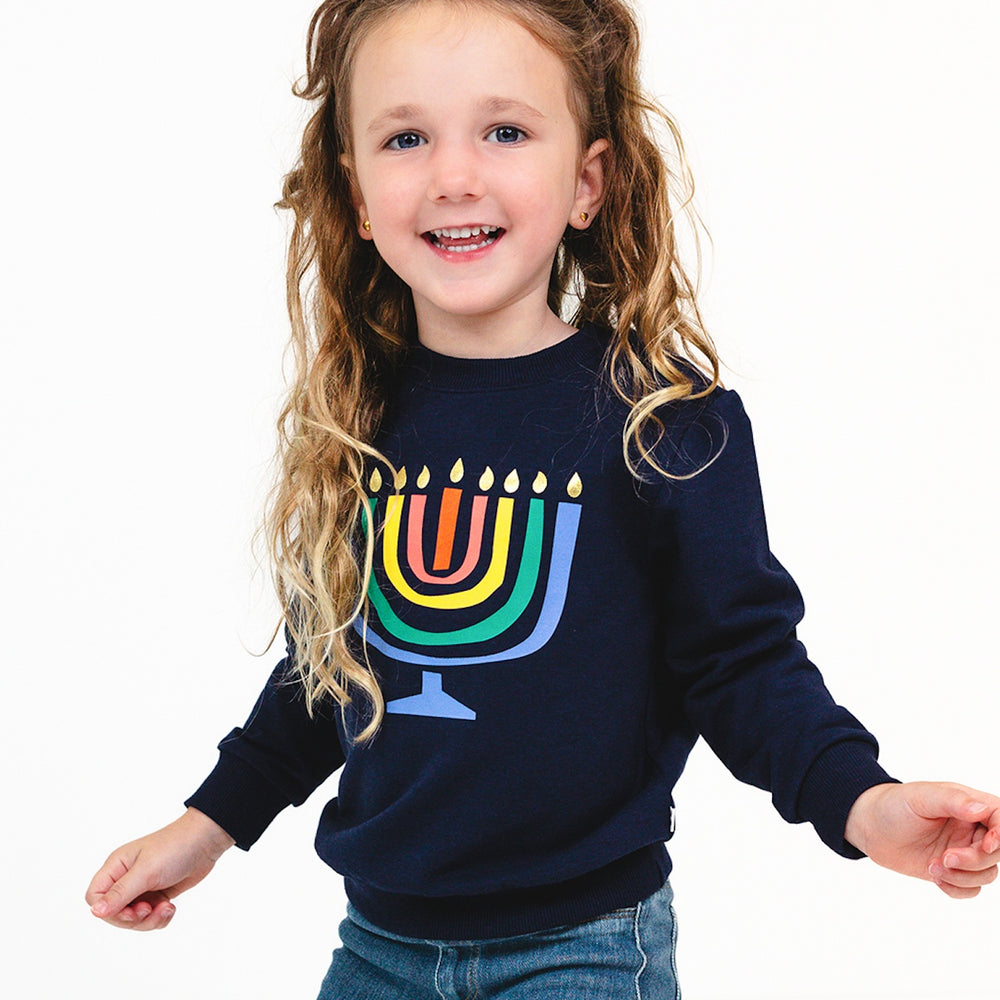 Close up image of a child wearing a Menorah Graphic Crewneck