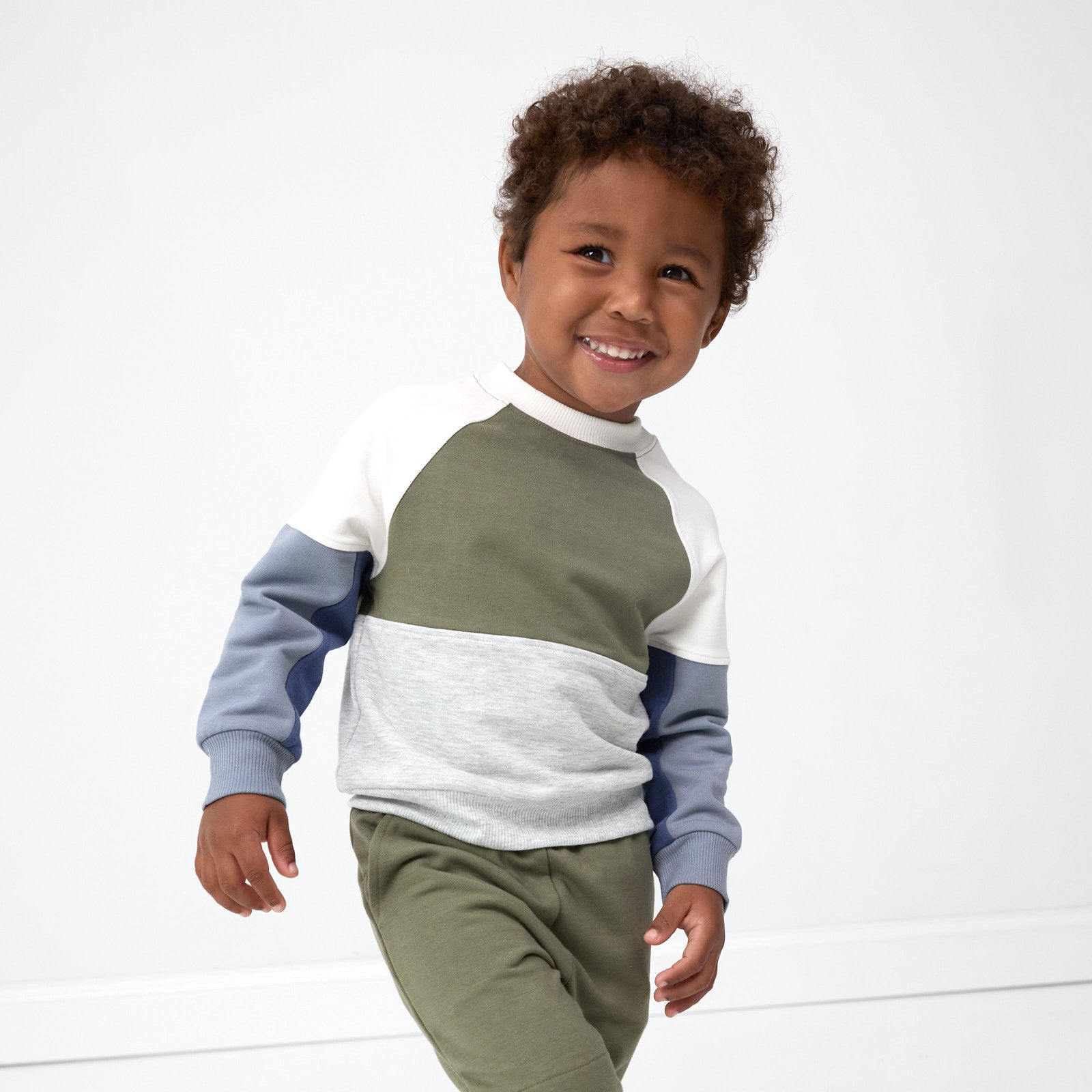 Smiling boy posing while wearing the Olive Panel Crewneck