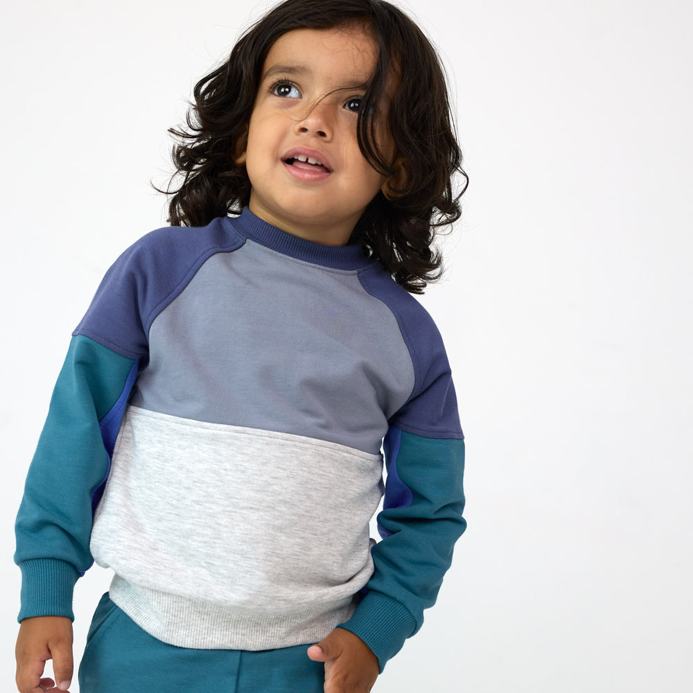 Child posing while wearing the Windy Sky Panel Crewneck