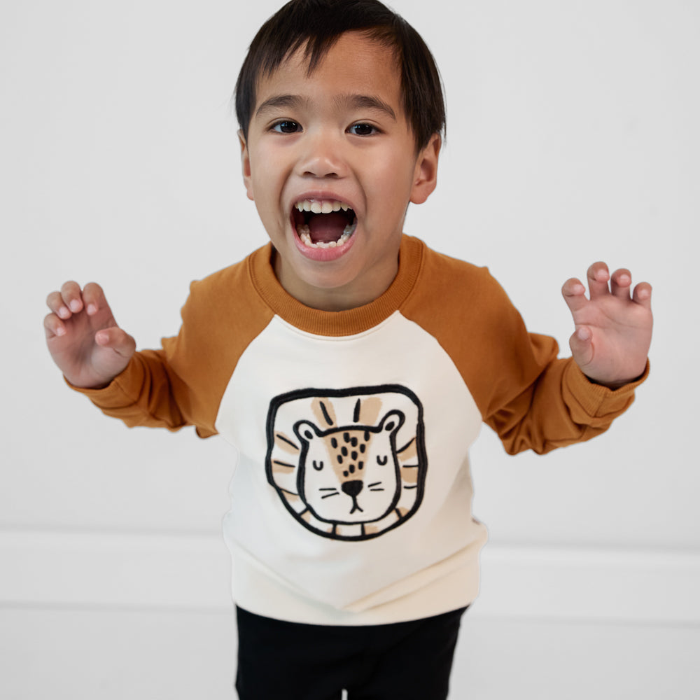 Child roaring like a lion wearing an Arctic raglan crewneck paired with black joggers