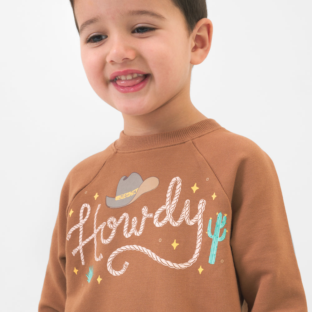 Close up image of a child wearing a Howdy crewneck sweatshirt