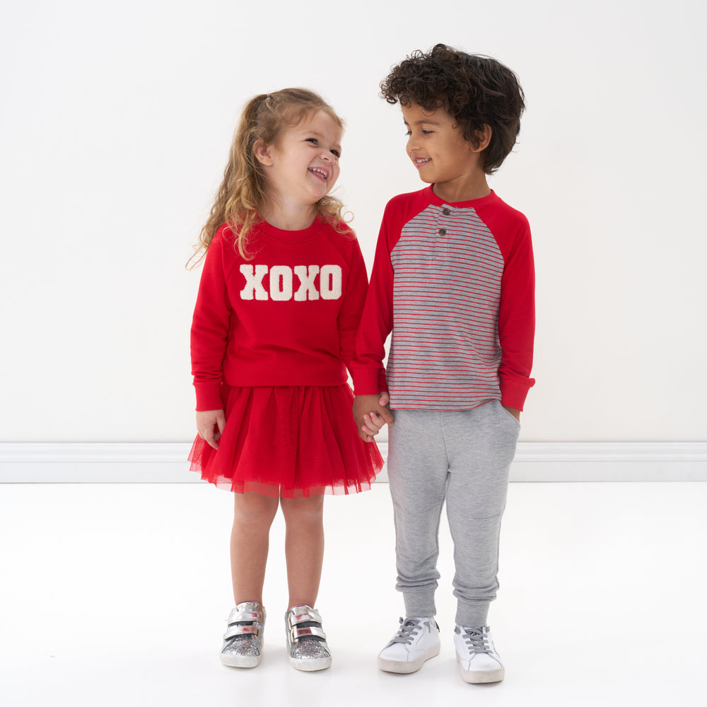 Click to see full screen - Two children holding hands wearing Valentine's Day by Little Sleepies outfits