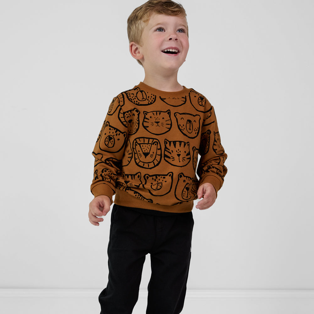 Child wearing an Amber Lions, Tigers & Bears crewneck sweatshirt with black animal illustrations, paired with black joggers