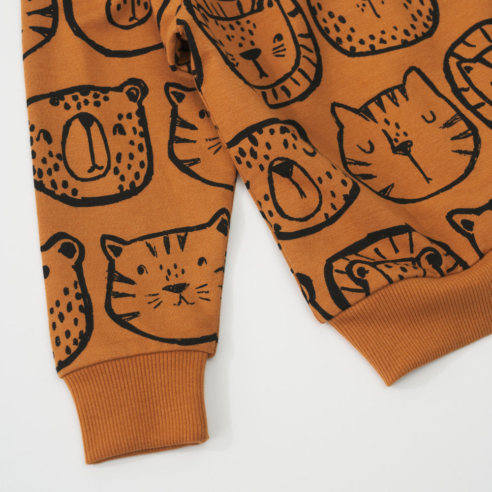 Close-up view of the sleeve cuff of an Amber Lions, Tigers & Bears crewneck sweatshirt with black animal illustrations