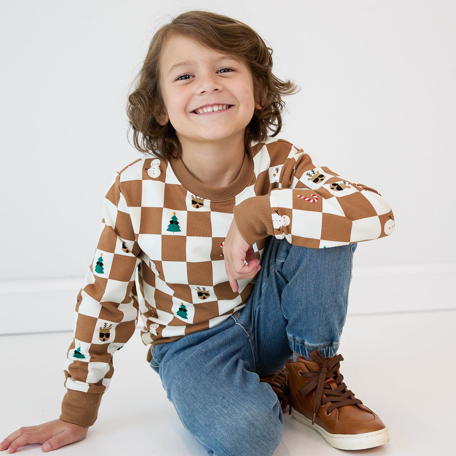 Child sitting on the ground wearing a Holiday Checks Crewneck Sweatshirt and Midwash Blue Denim Jogger