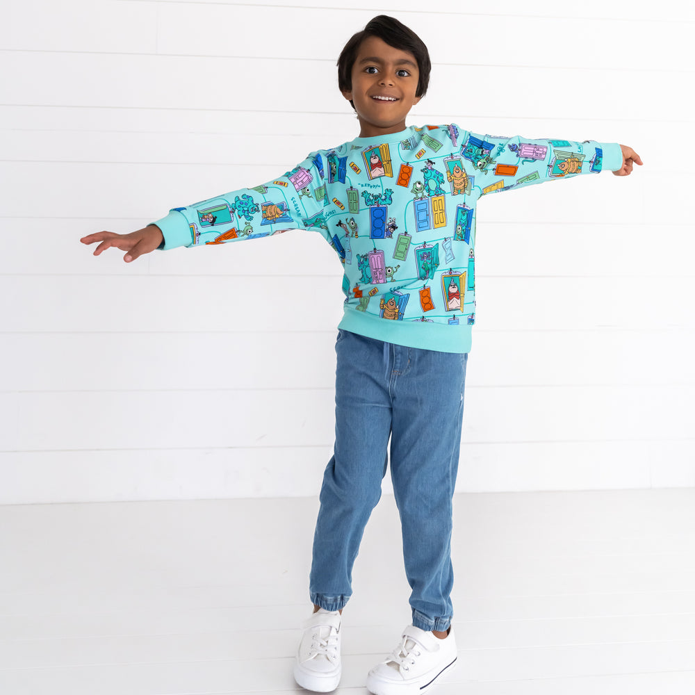 Boy posing while wearing the Disney Monsters, Inc. Scream Team Crewneck Sweatshirt and Midwash Play Joggers