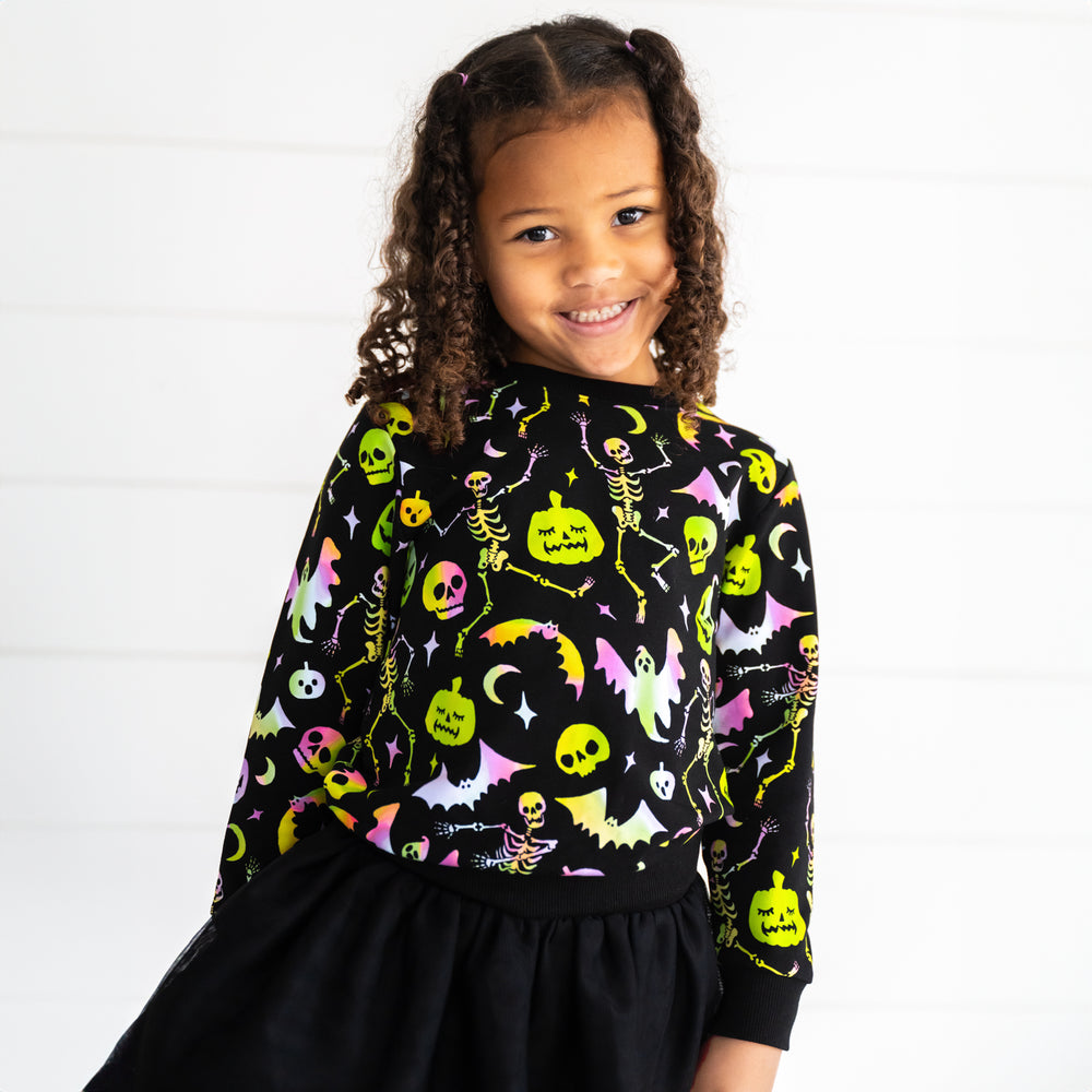 Close up image of a child wearing a Cool Ghouls Crewneck Sweatshirt and Black Tutu Skirt