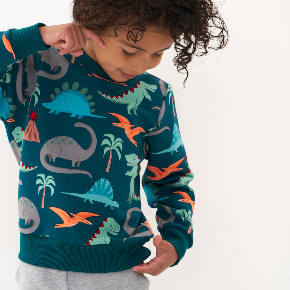 Click to see full screen - Alternate close up image of a child wearing a Teal Prehistoric Pals crewneck sweatshirt