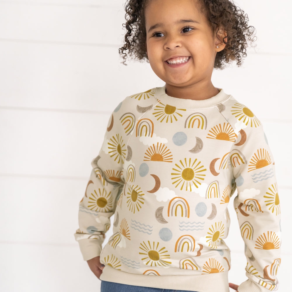 Close up image of a child wearing a Desert Sunrise Crewneck Sweatshirt