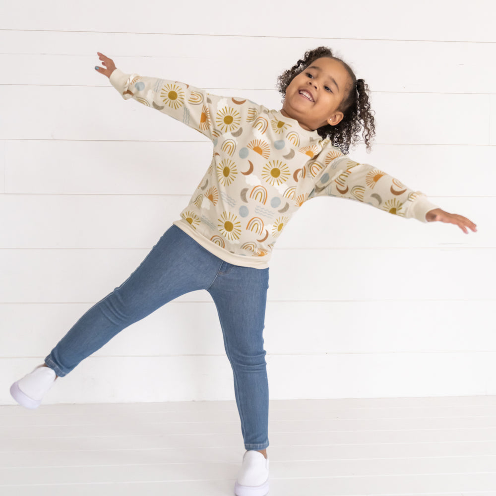 Image of a child wearing a Desert Sunrise Crewneck Sweatshirt and Midwash Blue Denim Jegging