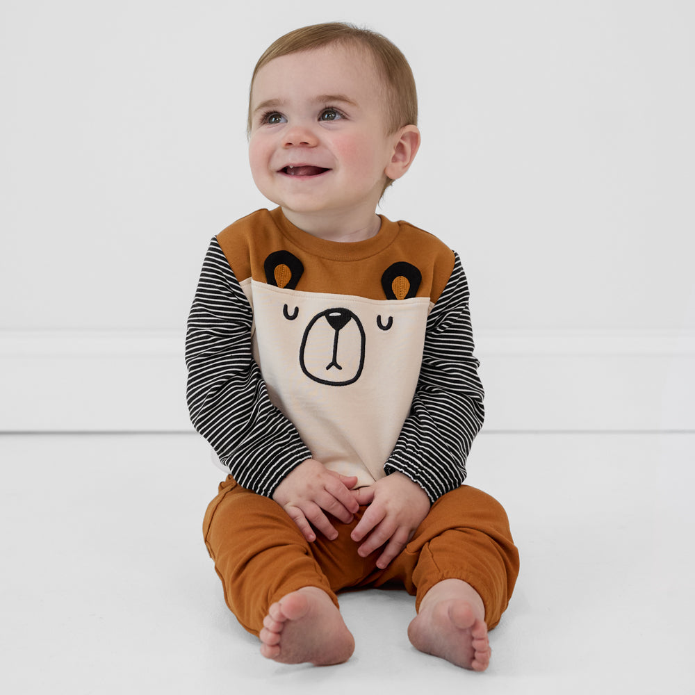 Child sitting on the ground wearing an Arctic Cinched Panel Crewneck, paired with golden brown joggers