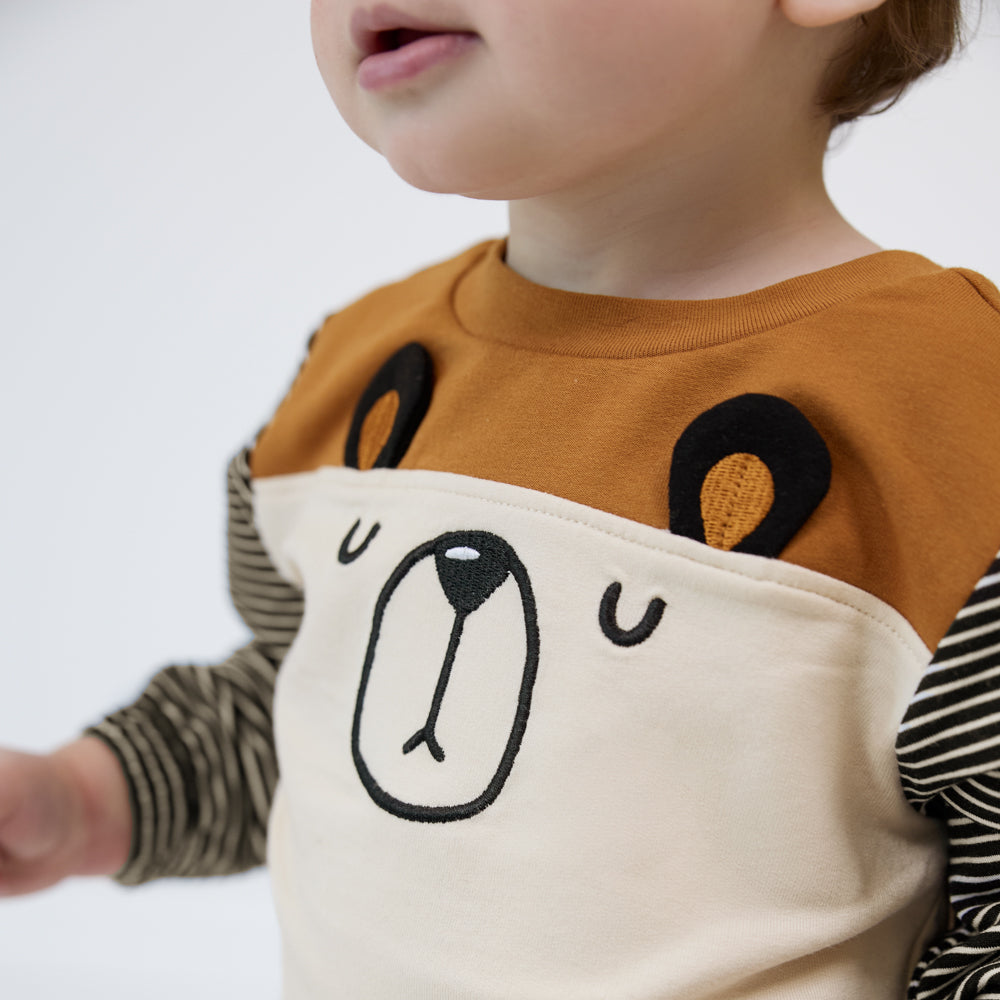 Close up view of a child wearing an Arctic Cinched Panel Crewneck with a bear face design