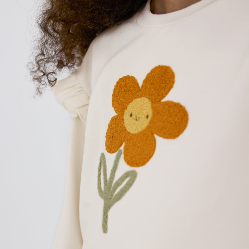 Close-up view of the daisy on an Arctic Flutter Crewneck worn by a child