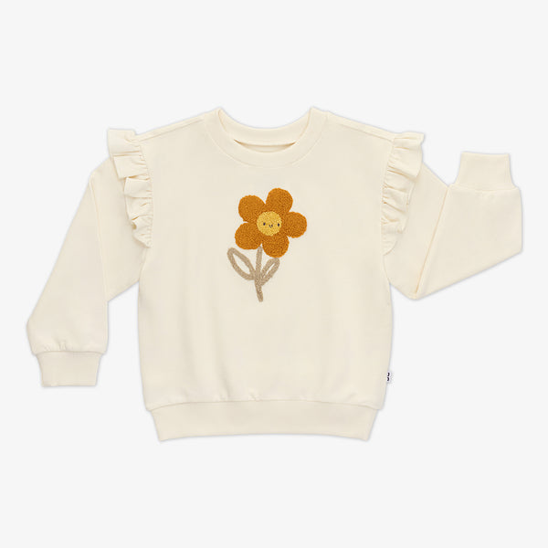 Flat lay of an off-white Arctic Flutter Crewneck featuring long sleeves, shoulder ruffles, and a daisy in the center