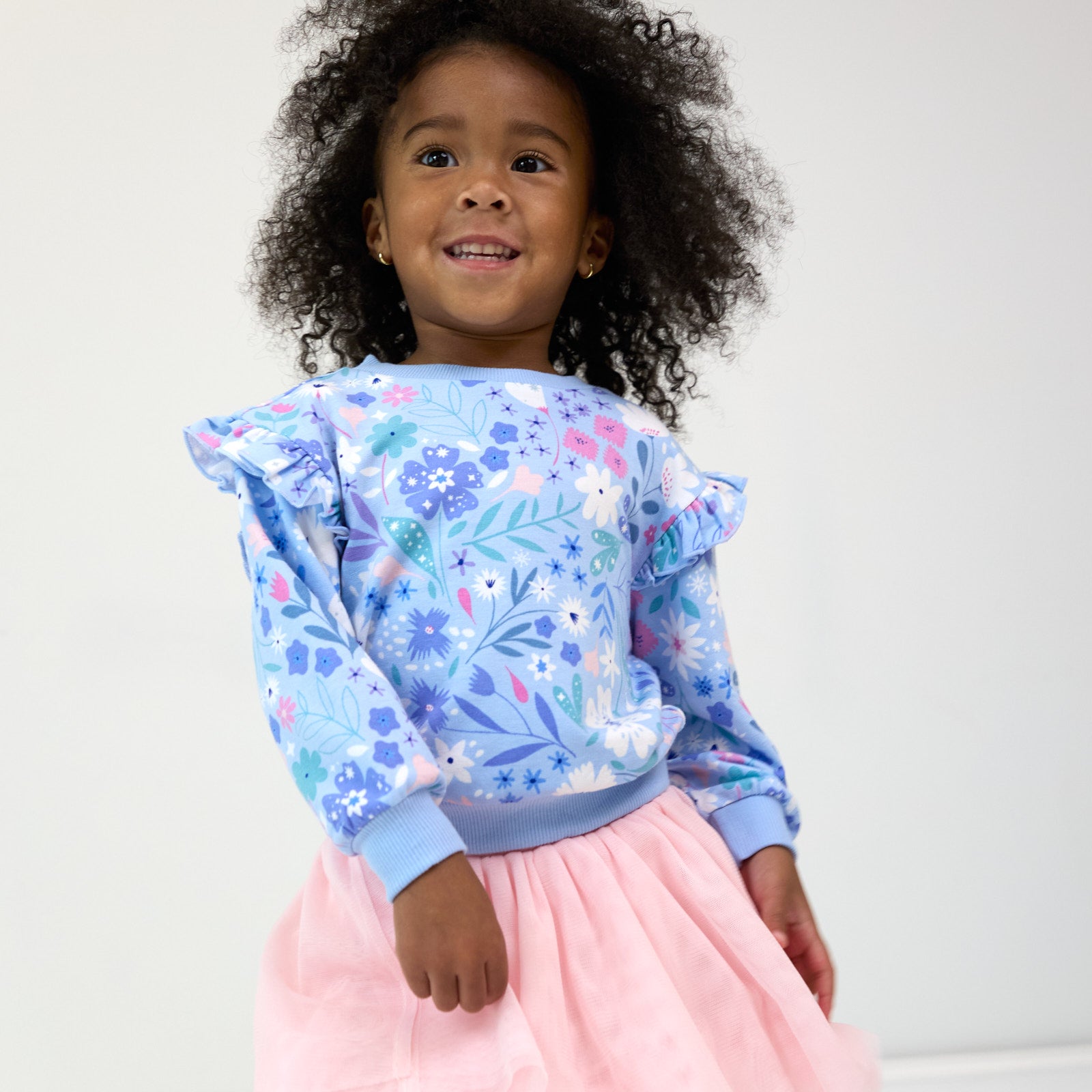 Smiling girl wearing the Magical Meadow Flutter Crewneck and Prima Pink Tutu Legging