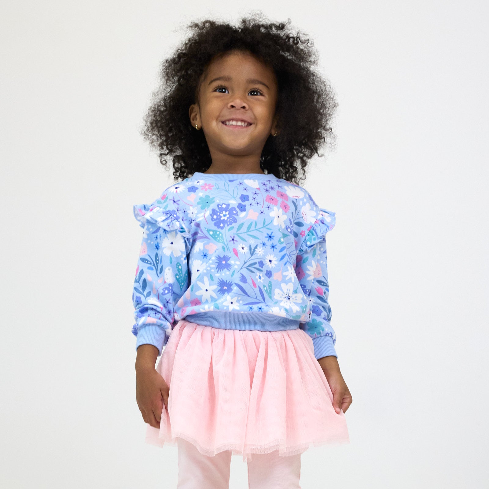 Smiling girl posing while wearing the Magical Meadow Flutter Crewneck and Prima Pink Tutu Legging