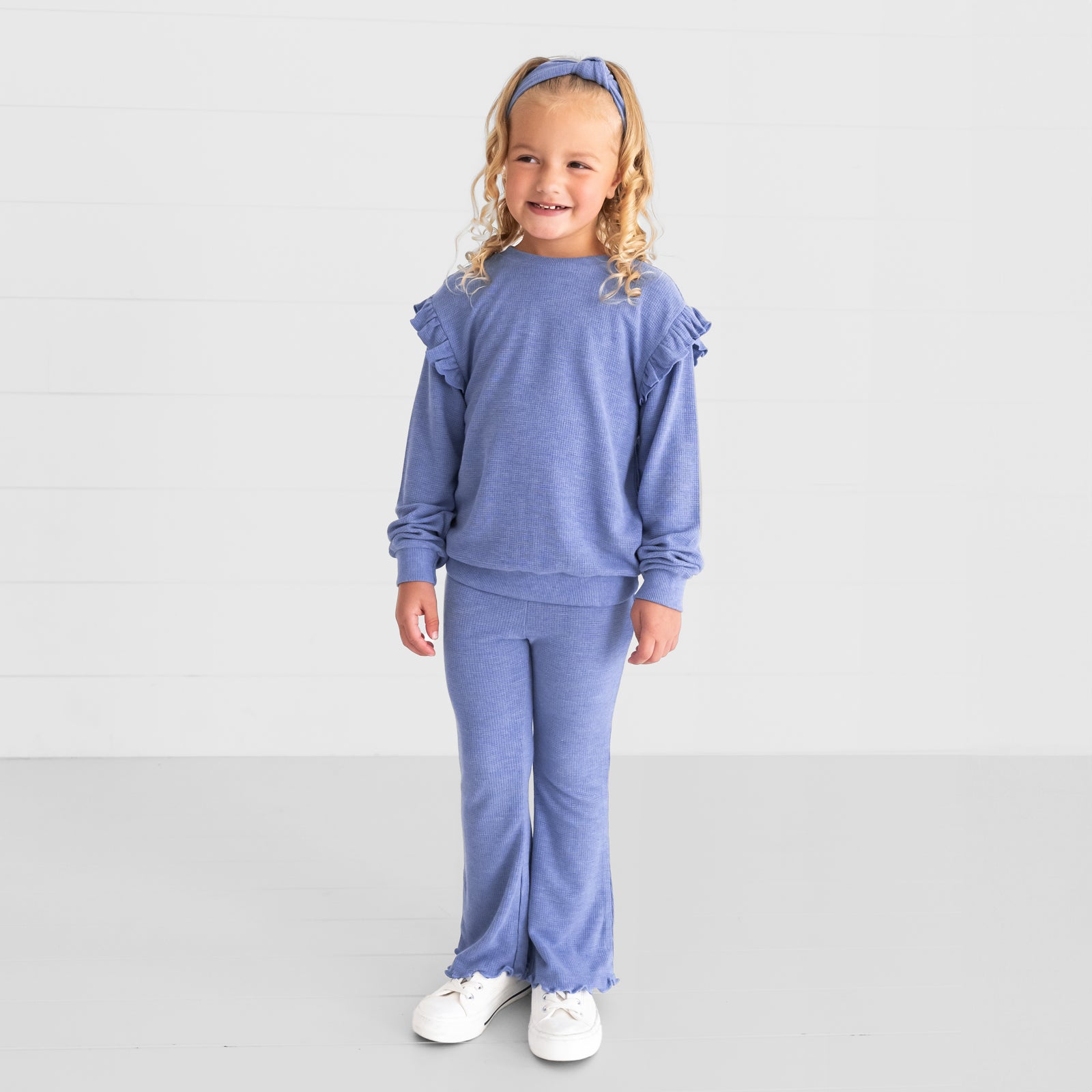 Image of a child wearing a Heather Lilac Waffle Flutter Crewneck, Flare Pant, and Knotted Headband