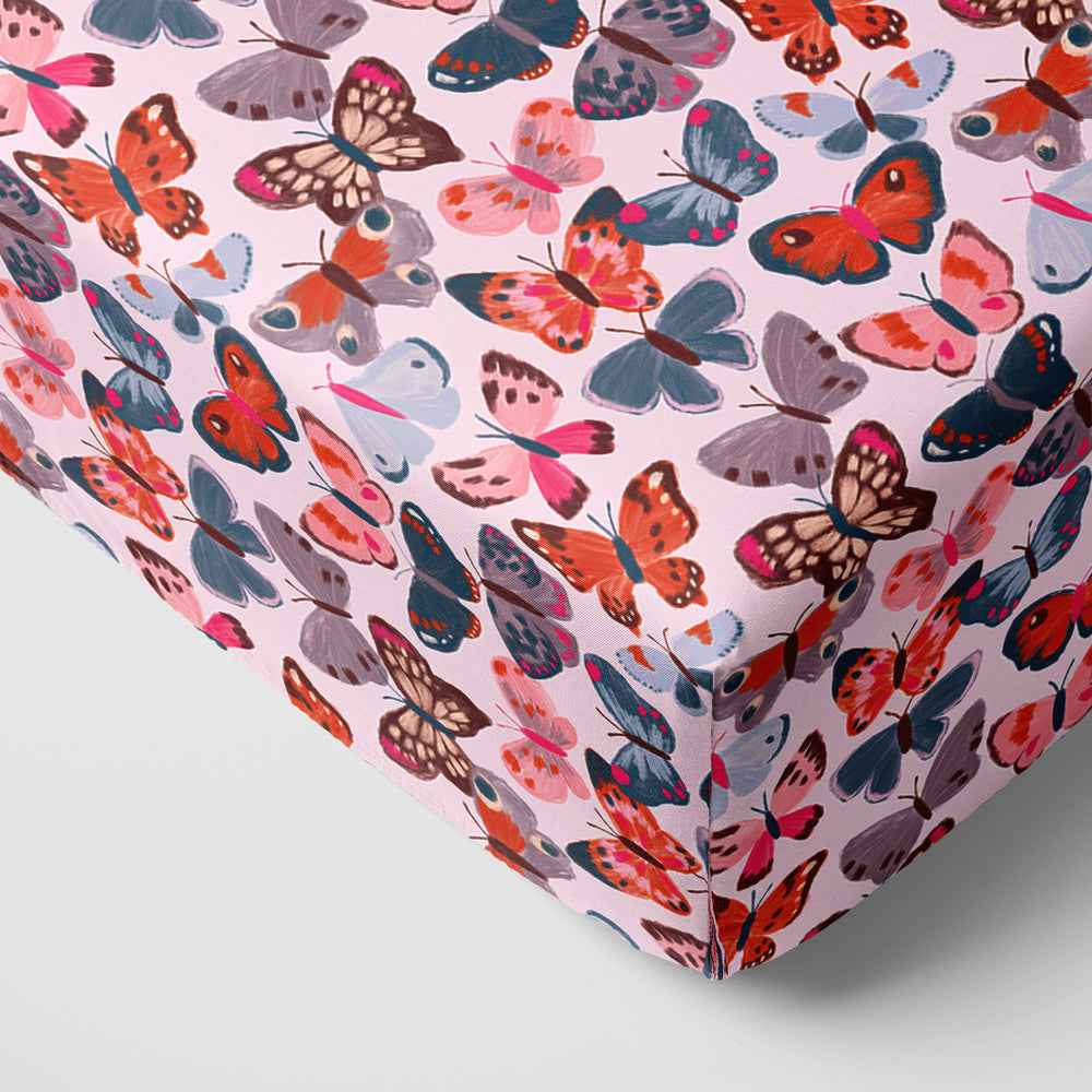 Close up image of a Butterfly Kisses fitted crib sheet on the corner of a mattress
