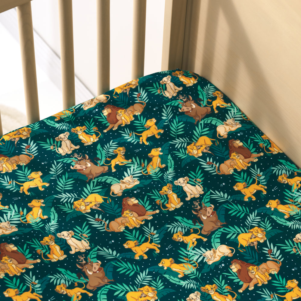 View of a Disney Simba's Sky fitted crib sheet in a wooden crib