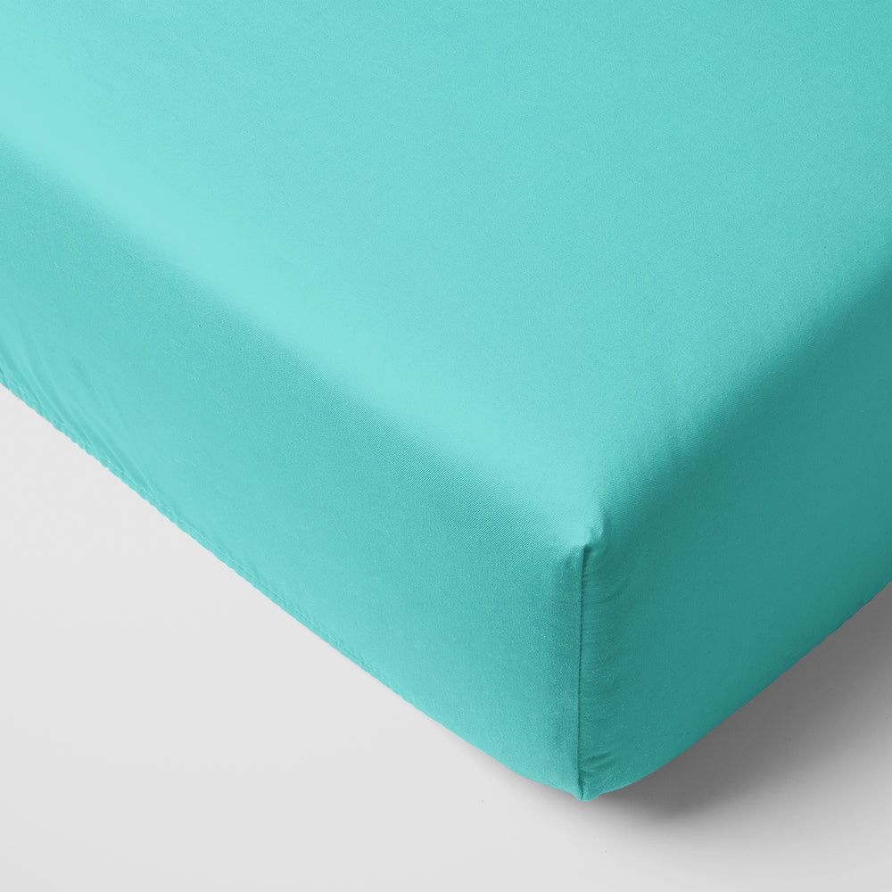 corner view of a Glacier Turquoise fitted crib sheet