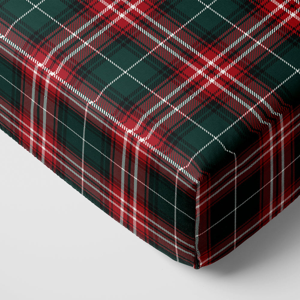 Image of a Fireside Plaid Fitted Crib Sheet on the corner of a mattress