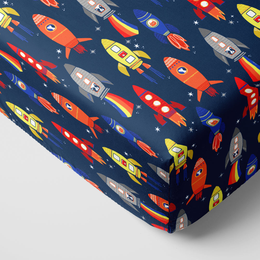 Corner view of a Navy Space Explorer fitted crib sheet