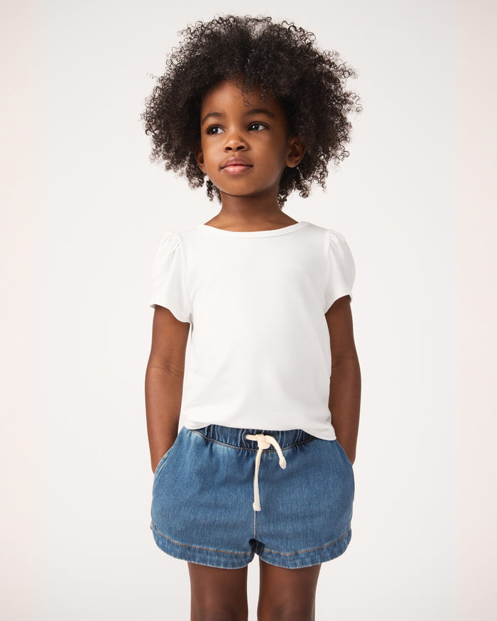 Close up of girl wearing the Soft White Puff Sleeve Tee with midwash blue denim shorts