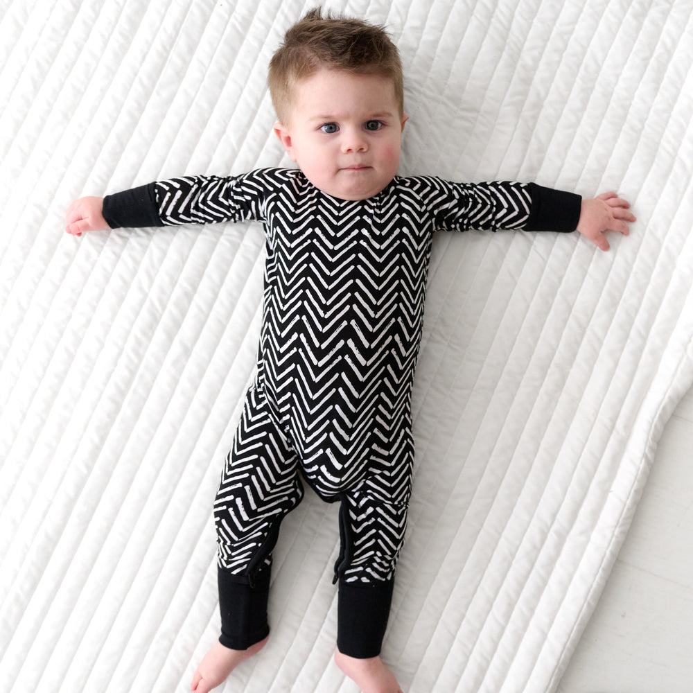 Child laying on a blanket wearing a Monochrome Chevron crescent zippy