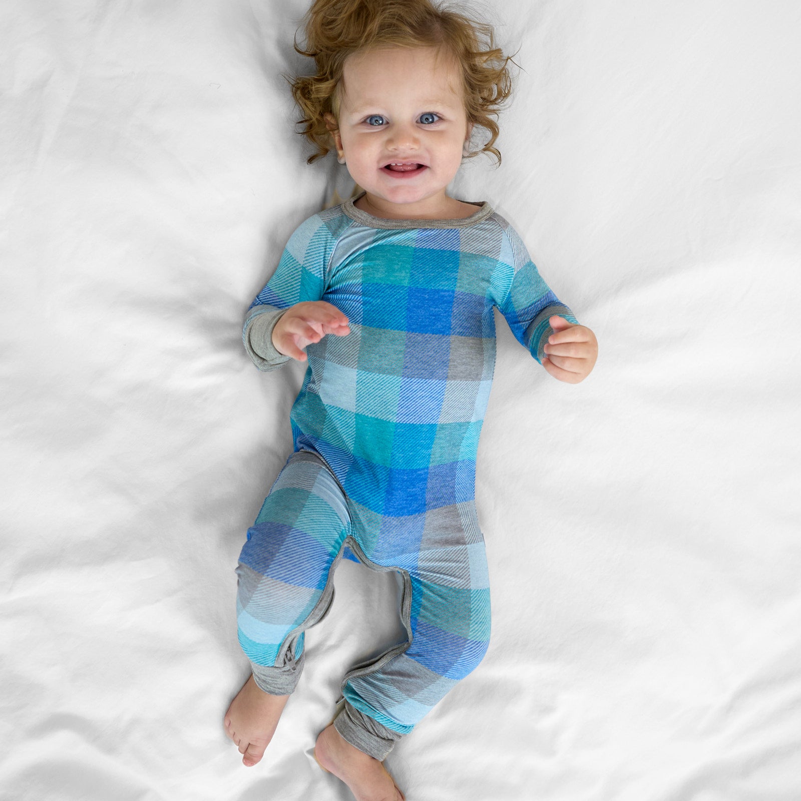 Child laying on a bed wearing an Arctic Plaid crescent zippy