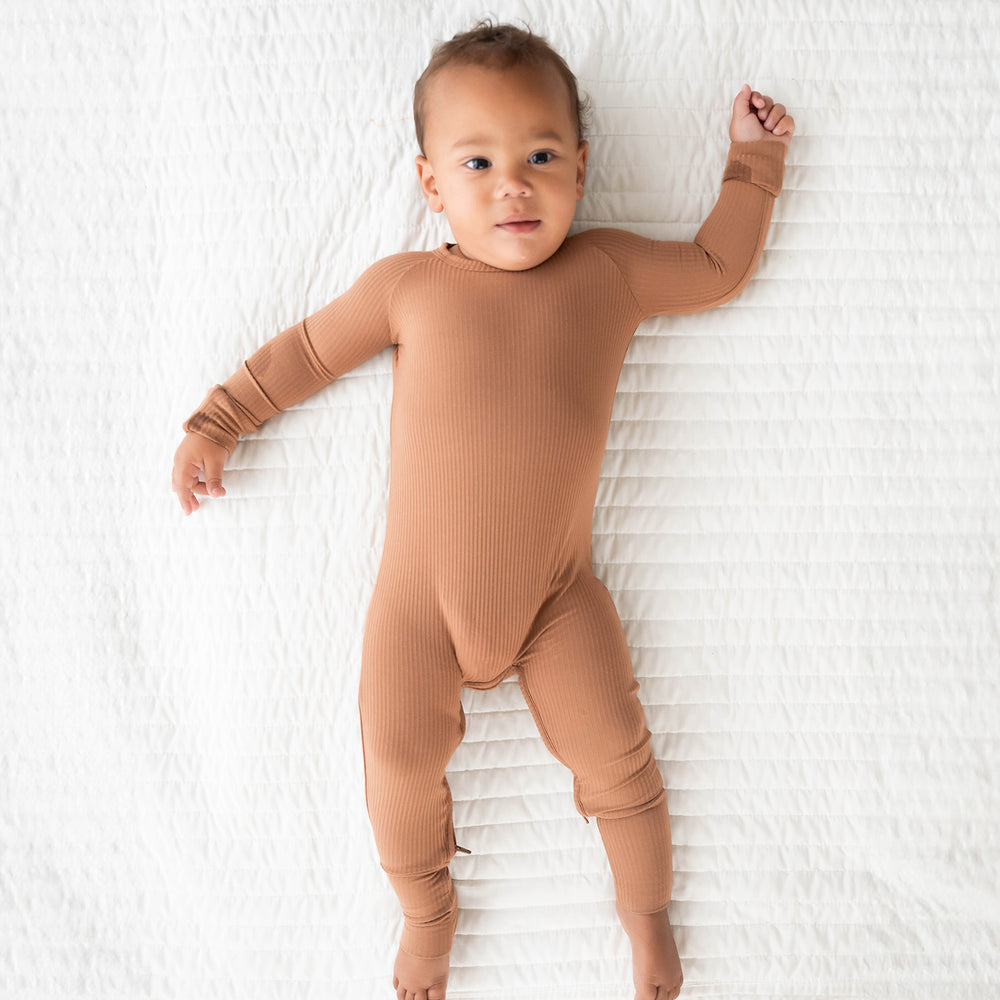 Child laying on a bed wearing a Caramel Ribbed crescent zippy