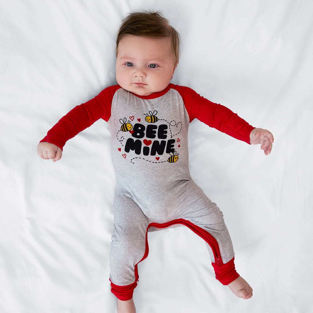 Child laying on a bed wearing a Bee Mine crescent zippy
