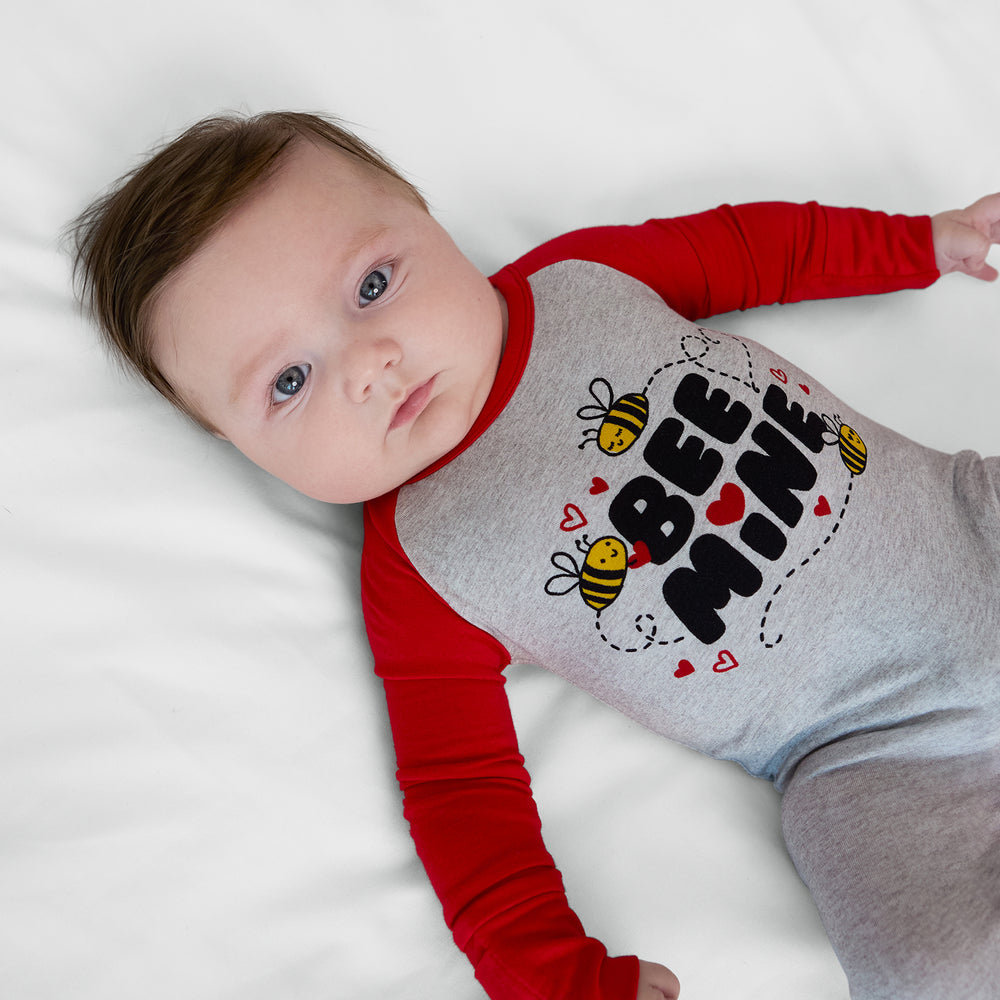 Close up image of a child laying on a bed wearing a Bee Mine crescent zippy
