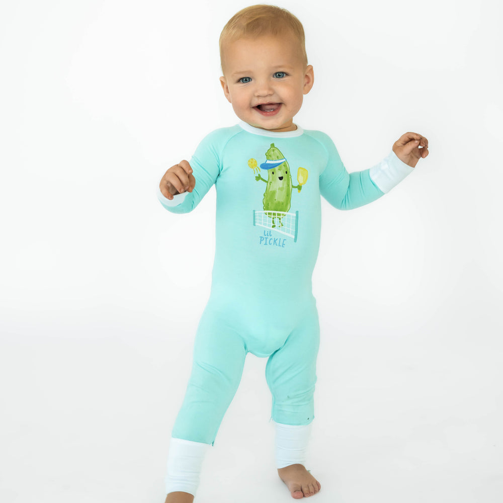 Baby standing while wearing the Pickle Power Crescent Zippy