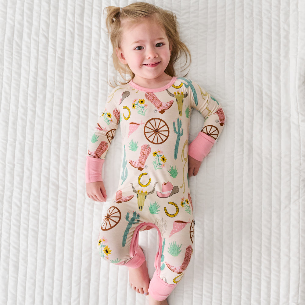 Child laying on a bed wearing a Pink Ready to Rodeo Crescent Zippy