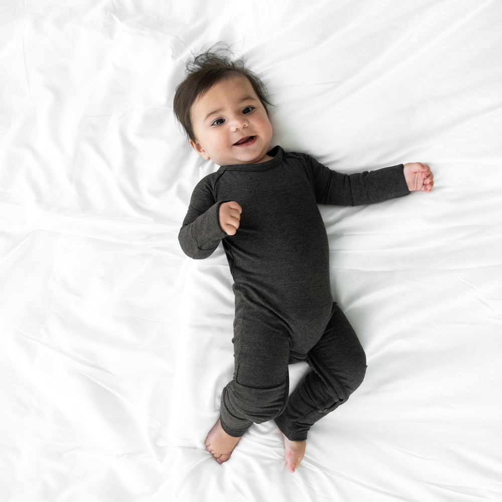 Alternate image of a child laying on a bed wearing a Cozy Heather Black crescent zippy