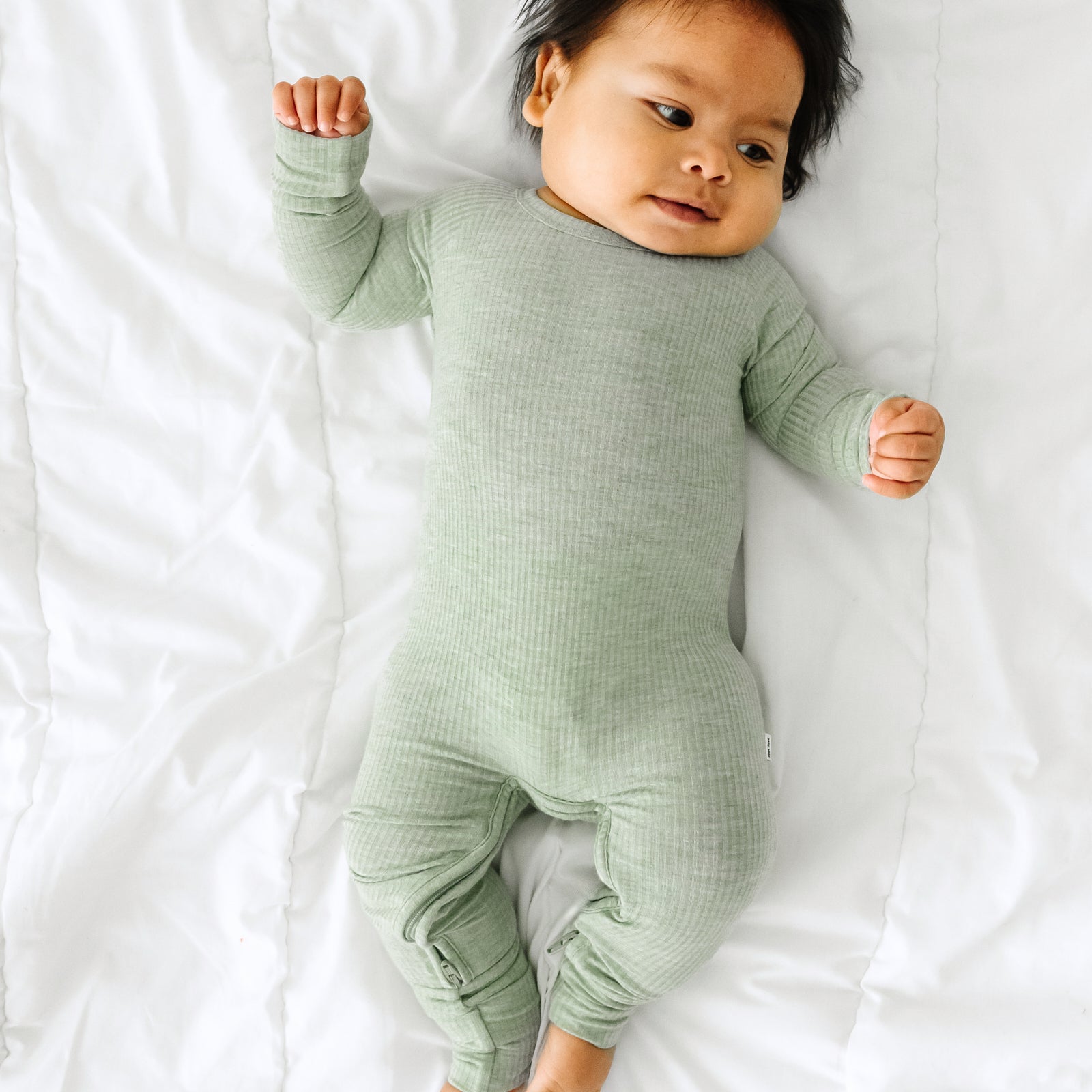 Alternate image of a child laying on a bed wearing a Heather Sage crescent zippy