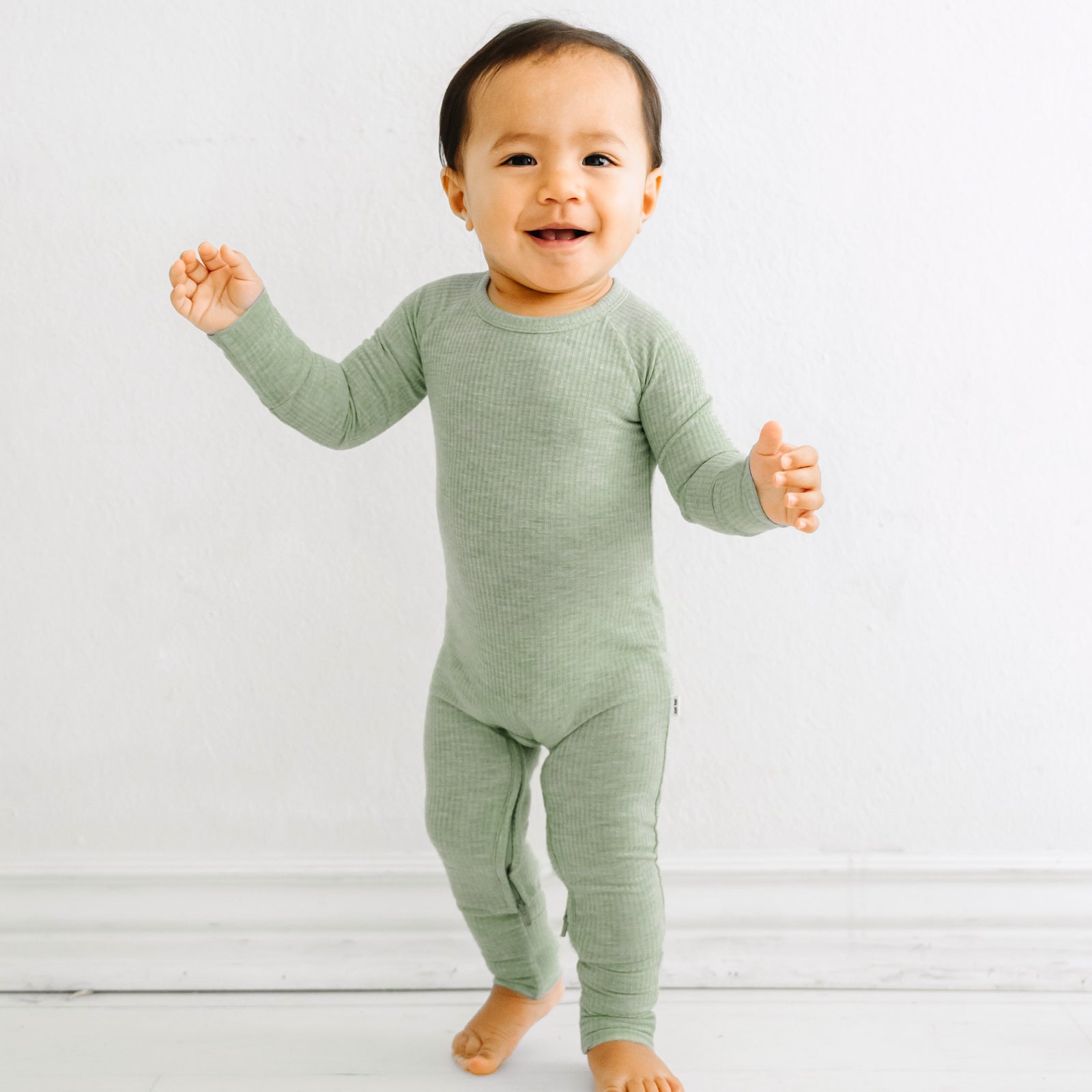 Child playing wearing a Heather Sage crescent zippy