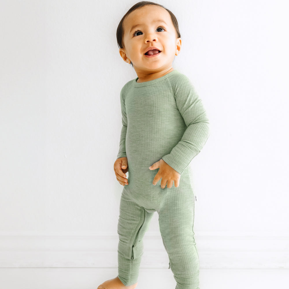 Child standing wearing a Heather Sage crescent zippy