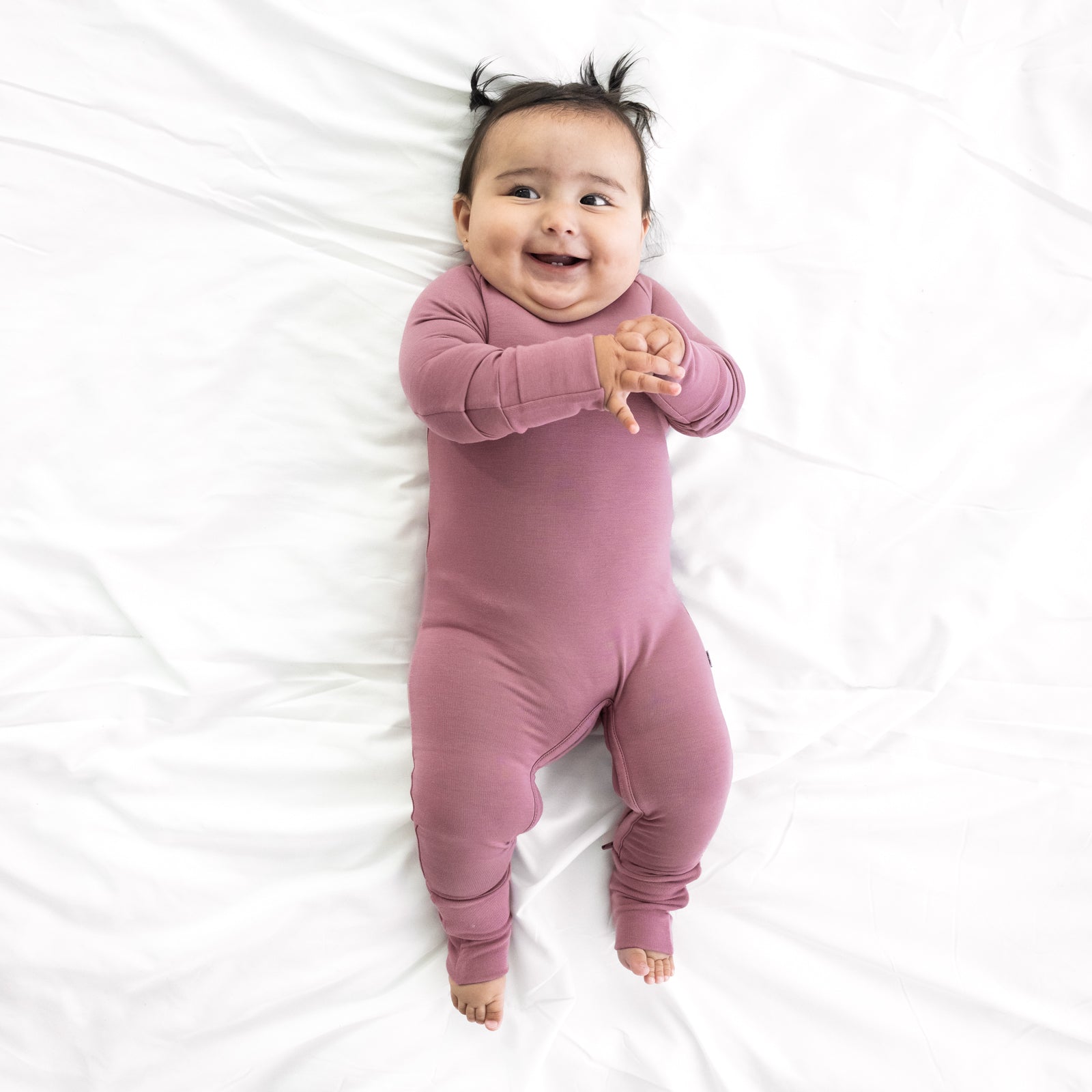 Child on a bed wearing a Cozy Dusty plum crescent zippy