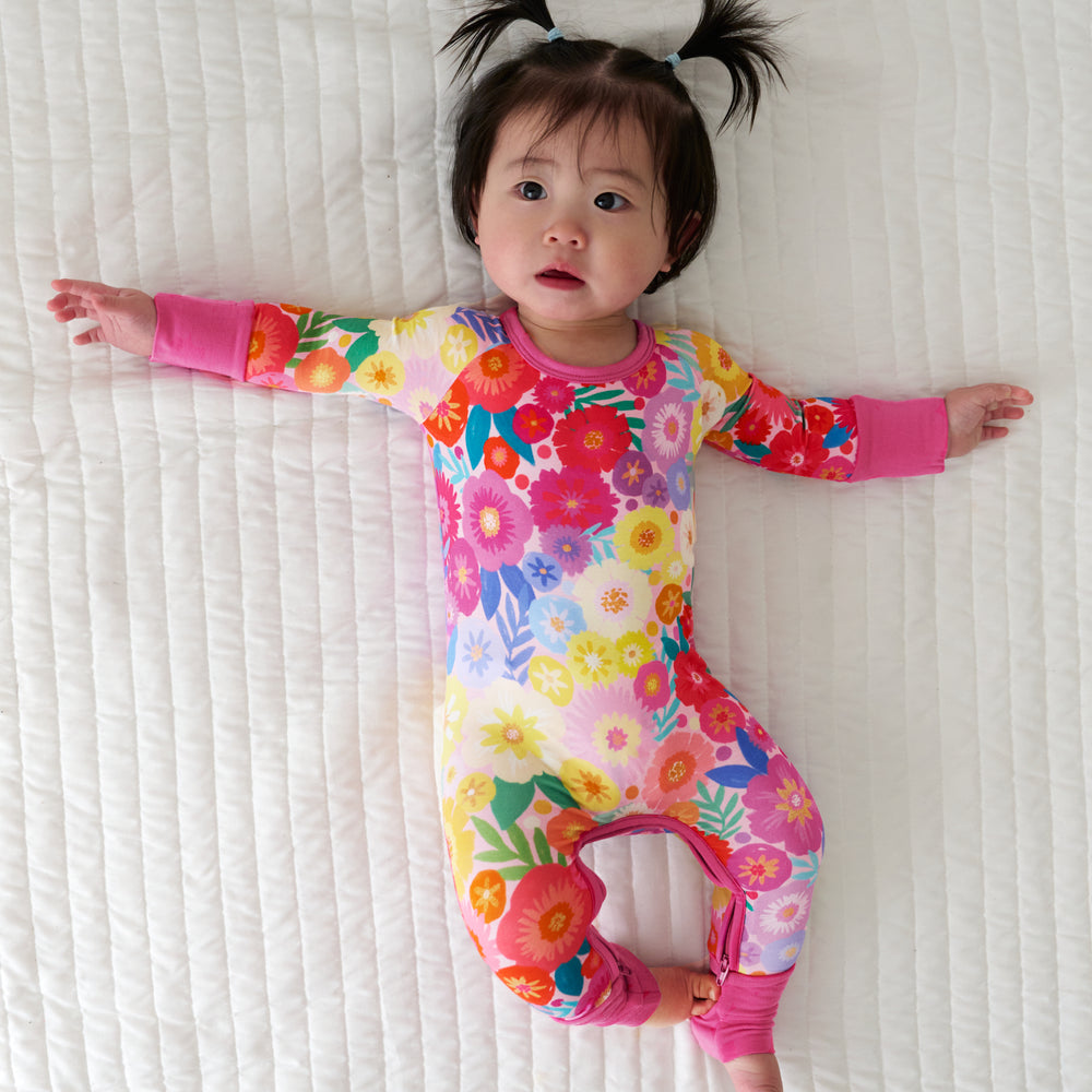 Child laying on a blanket wearing a Rainbow Blooms crescent zippy